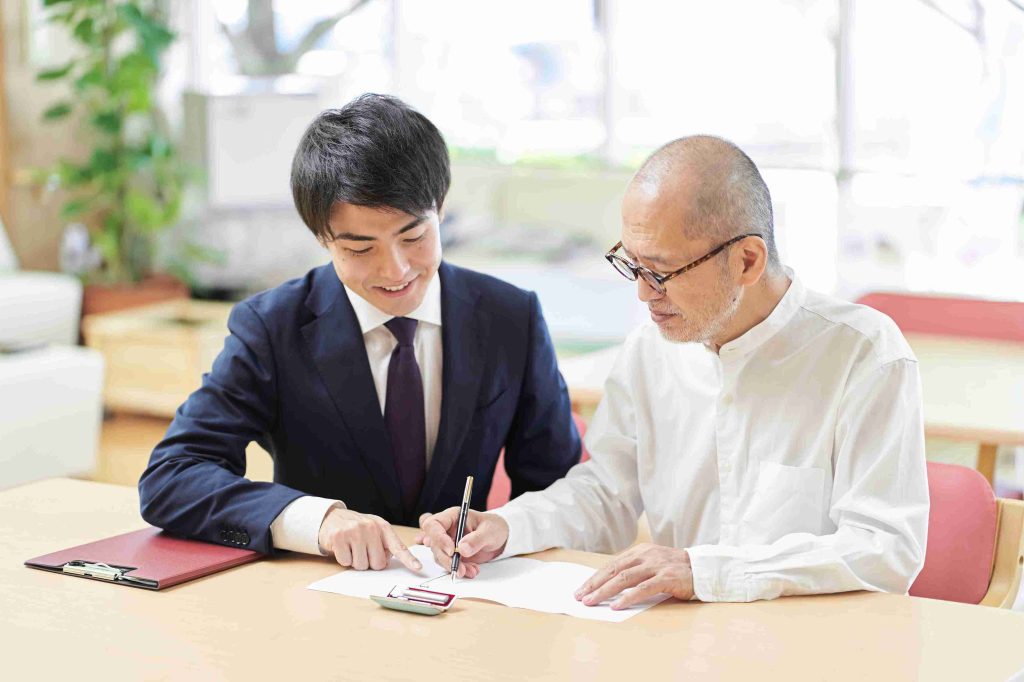 elderly man signing a document assisted by a lawyer