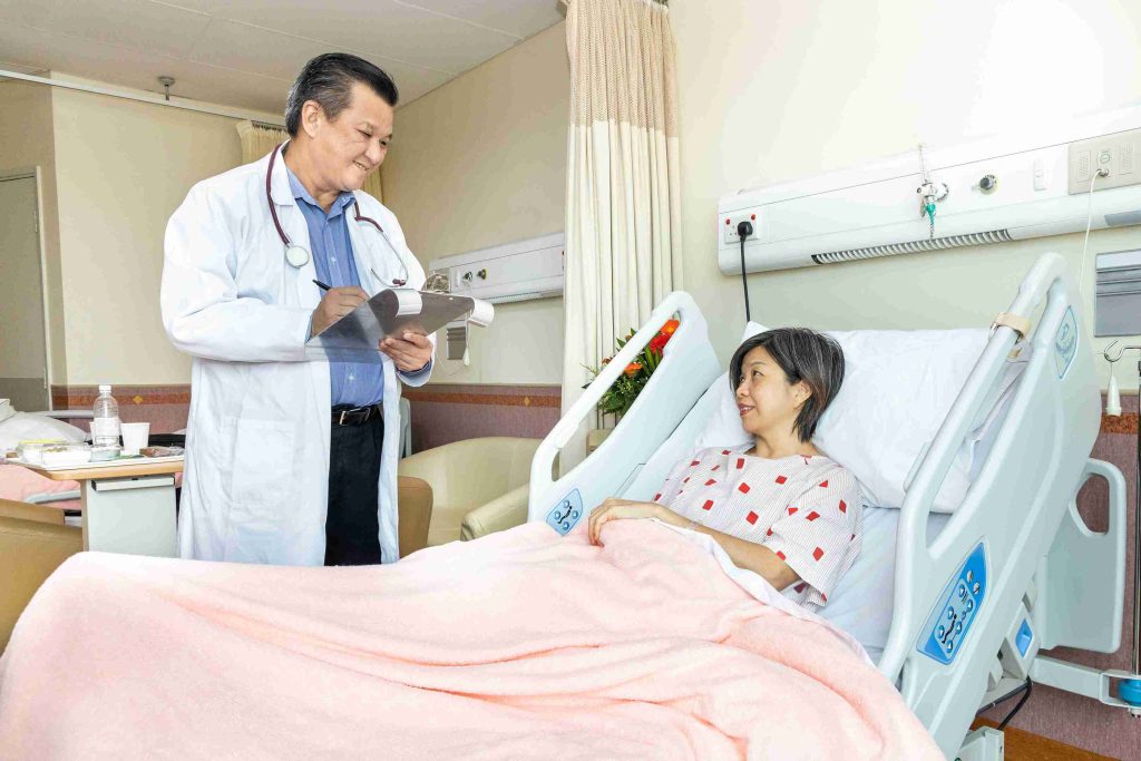 doctor speaking with female patient lying in hospital bed