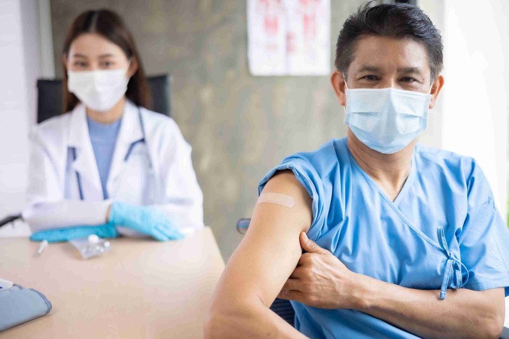 male patient with doctor showing off his vaccinated arm