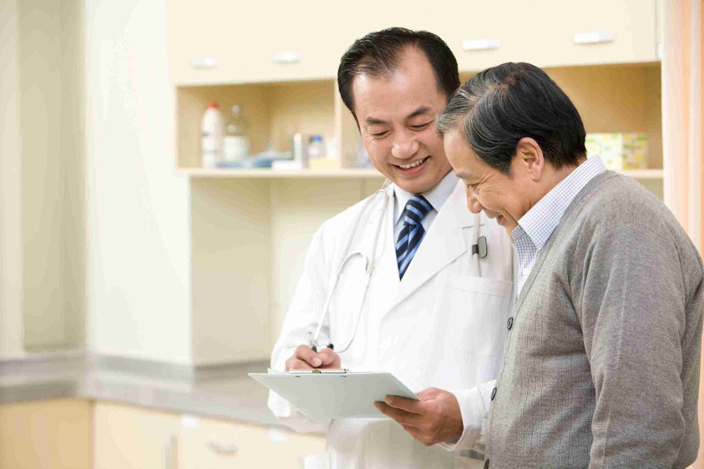 doctor smiling and showing a male patient a chart