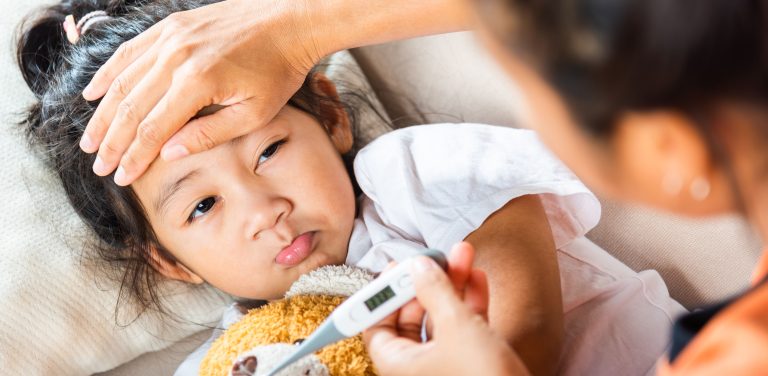 mother looking at thermometer and her child with fever