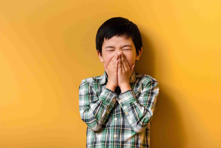 young asian boy covering his mouth
