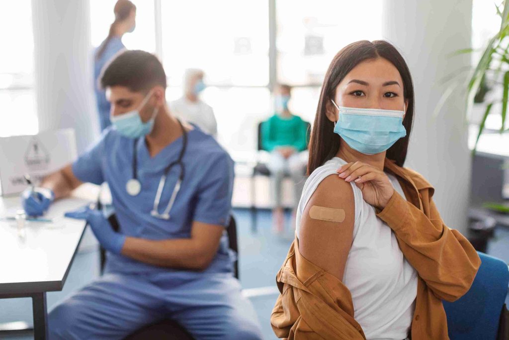 asian lady showing off her vaccinated arm