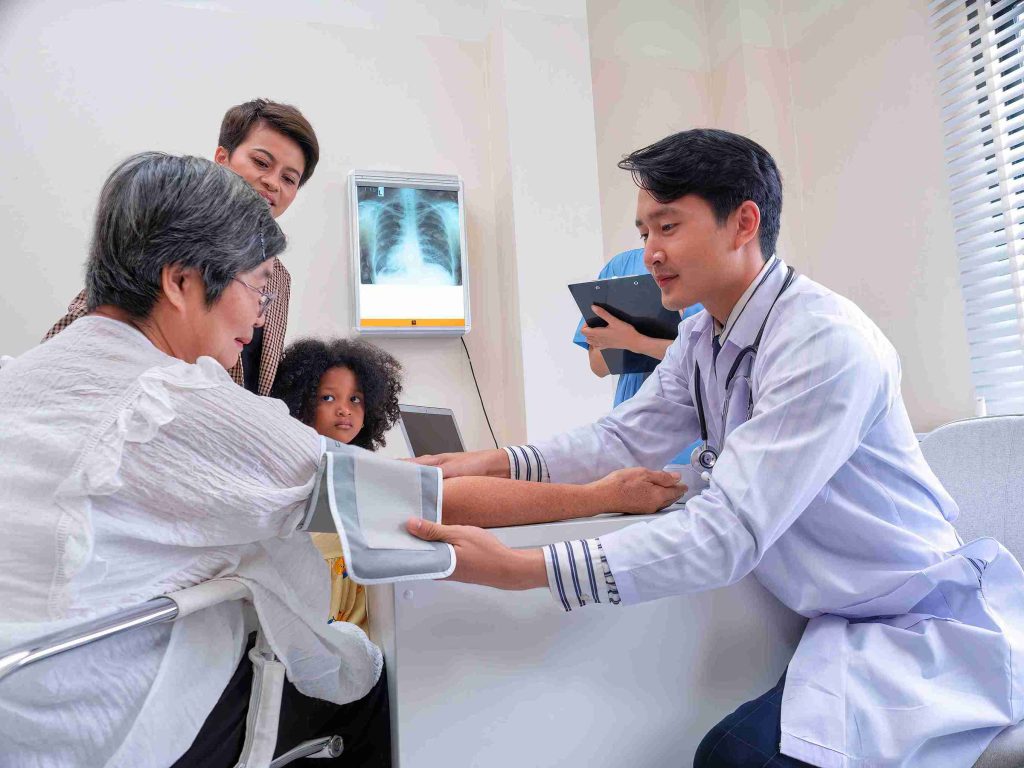 young male doctor checking the bp of an old patient