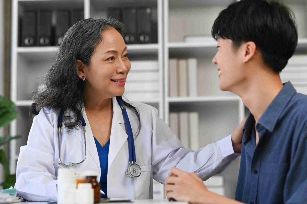 elderly female doctor speaking with a young male patient