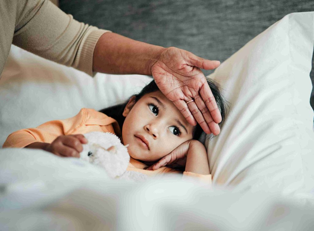 Mother putting hands on a little girl's forehead