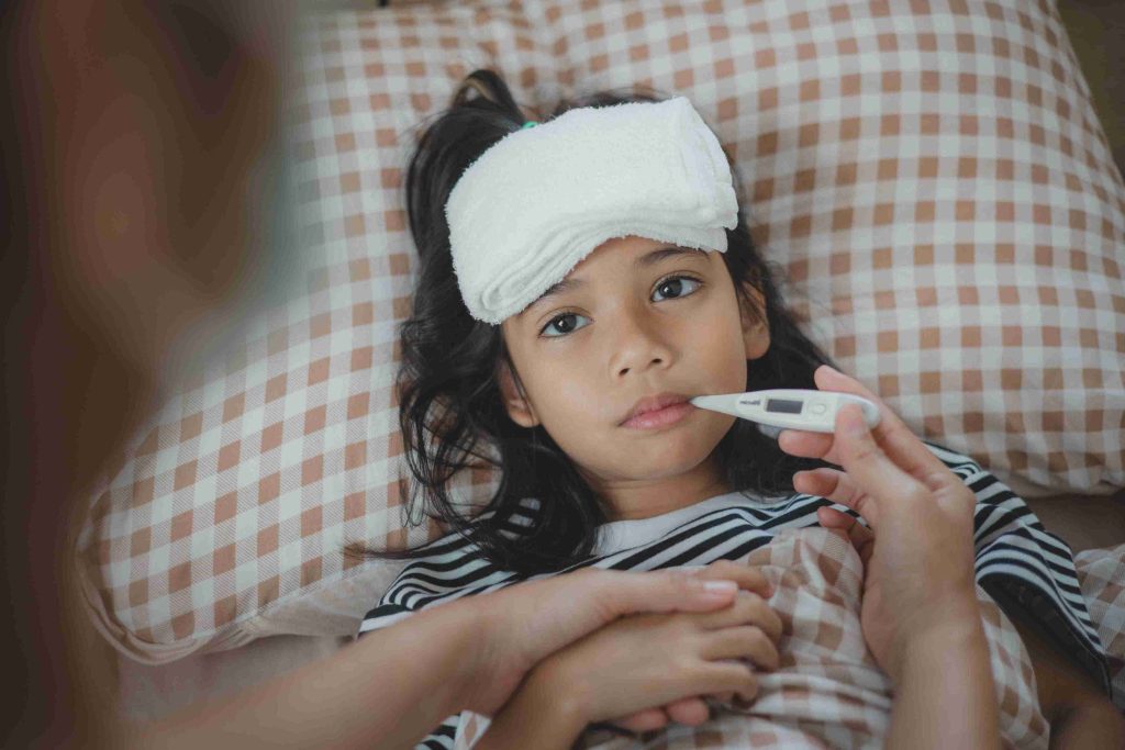 young girl lying in bed with fever