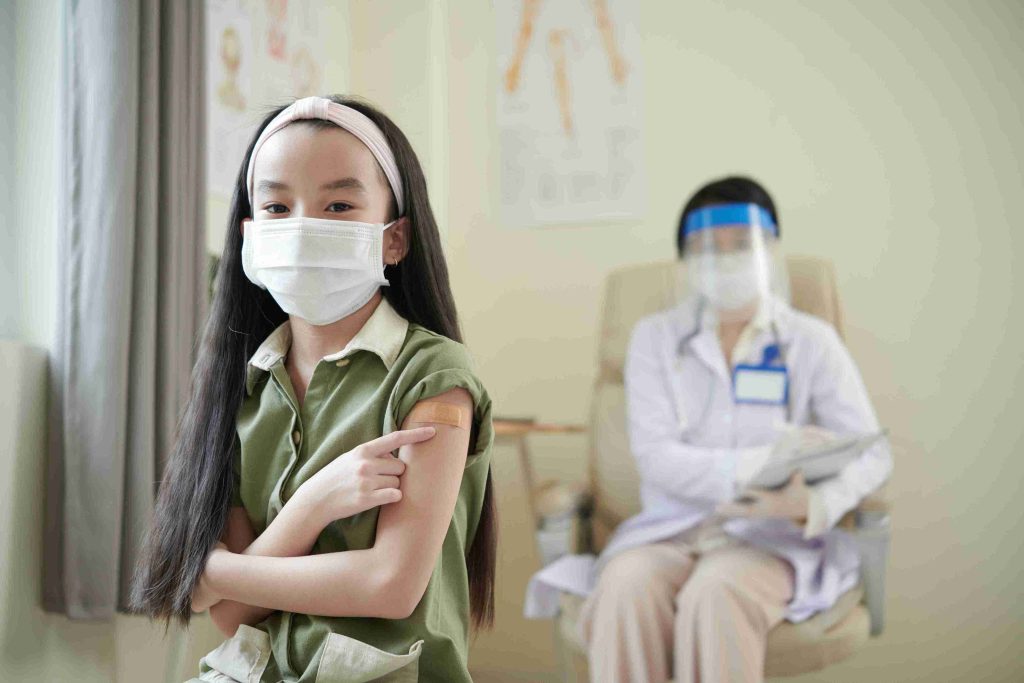 child pointing to her vaccinated arm
