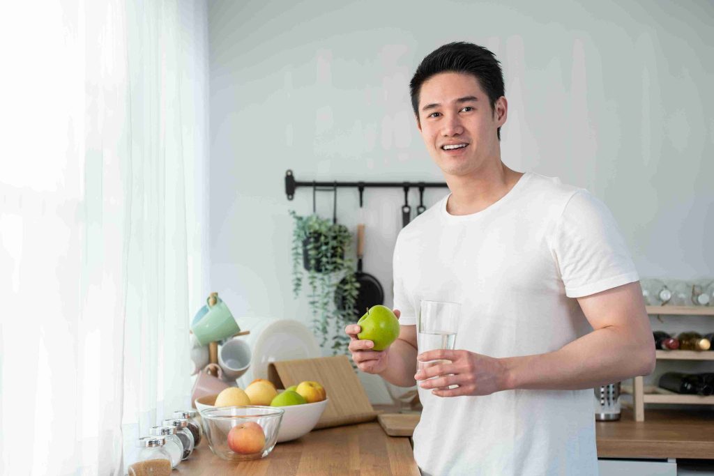 photo of male holding an apple and a glass of water
