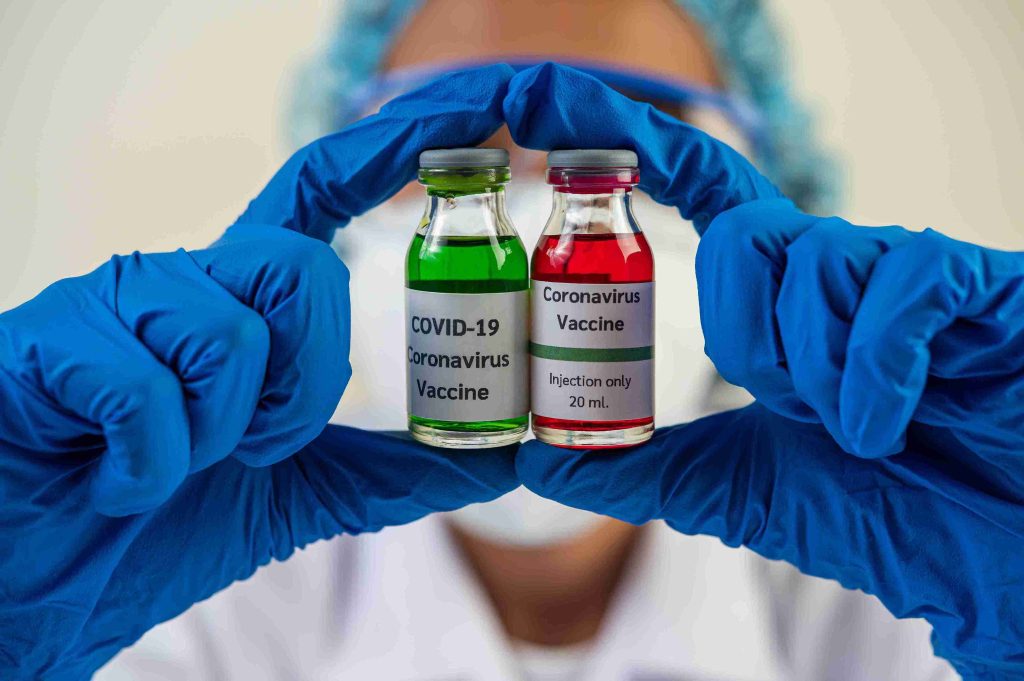 healthcare worker showing 2 vials of COVID-19 vaccine