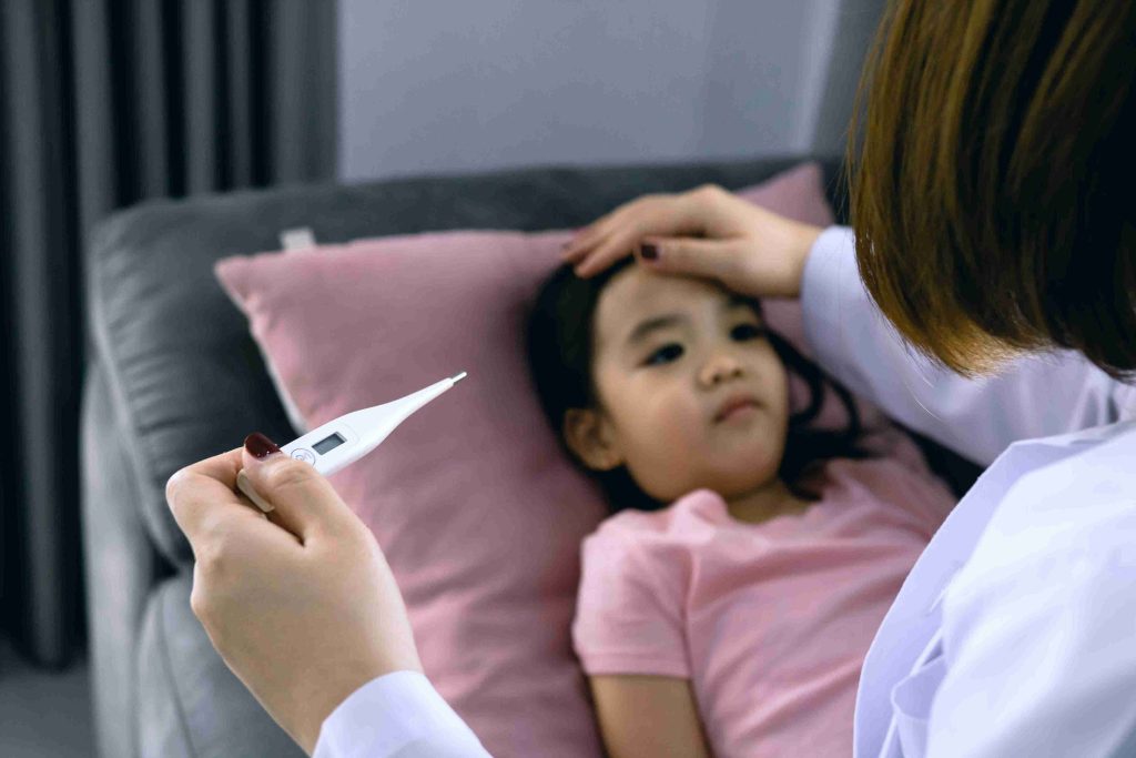 little girl lying on bed with fever