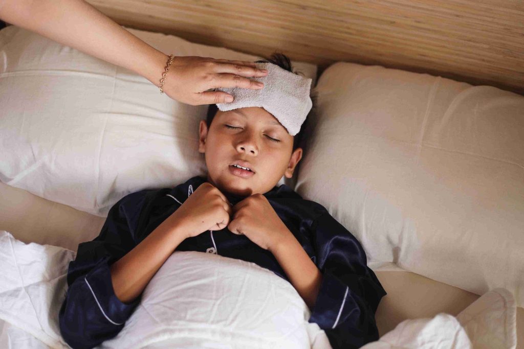 little boy lying in bed with fever
