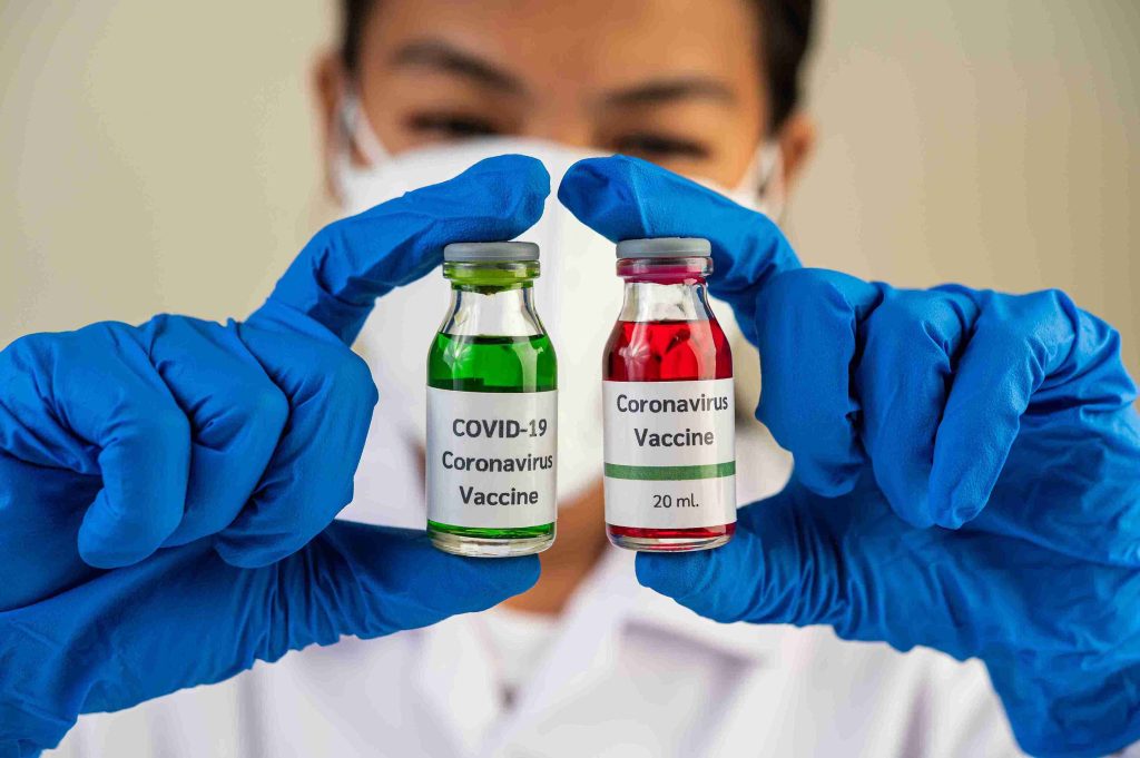 healthcare worker showing 2 vials of COVID vaccine