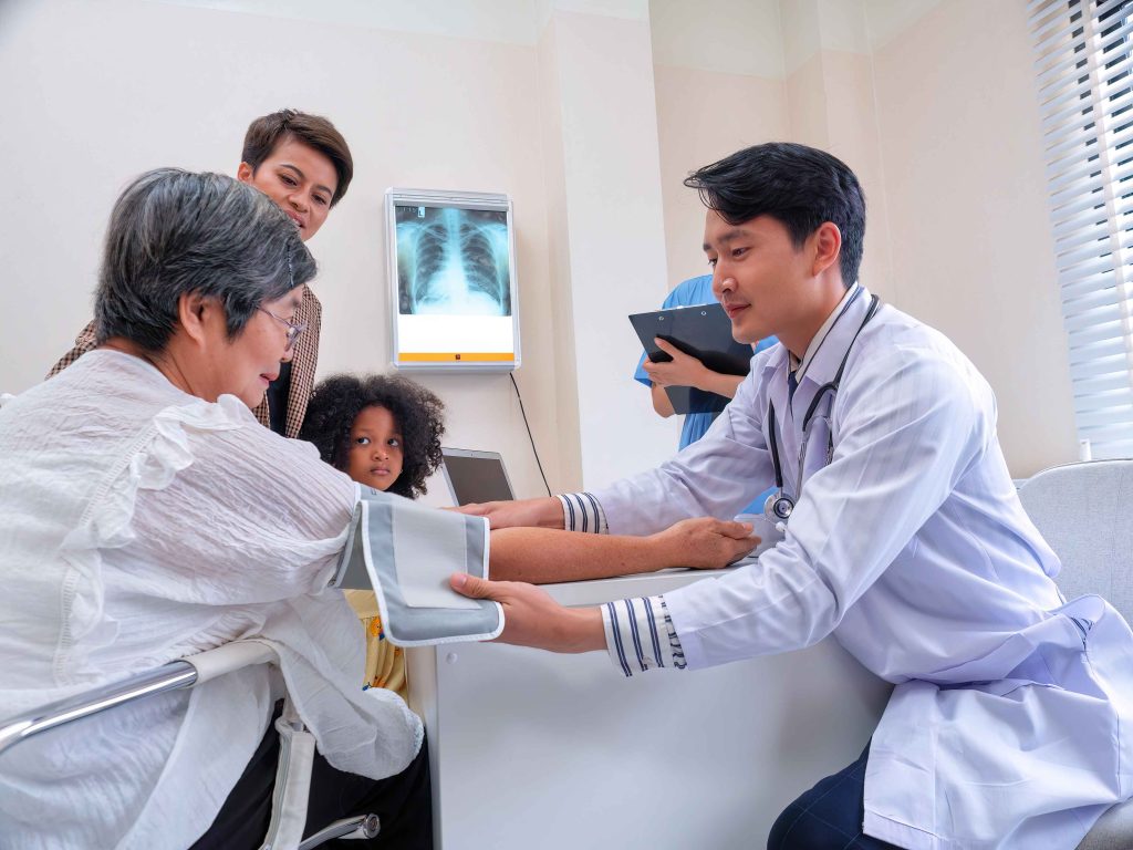 male doctor checking the blood pressure of an elderly patient