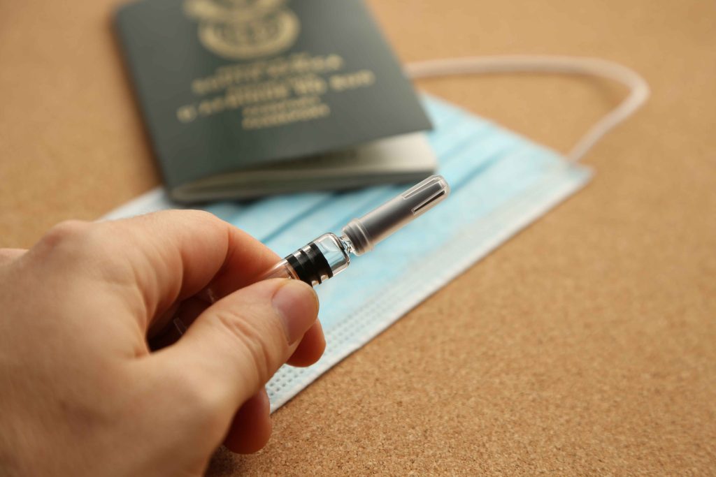 picture of a passport, medical mask, and vaccine needle