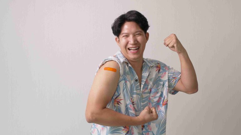 Smiling Asian male showing off his flu vaccination.