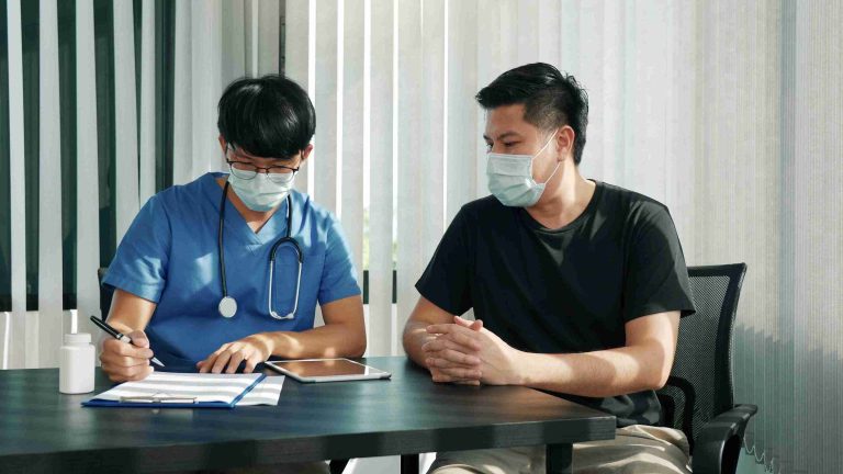 Asian worker speaking with his doctor.