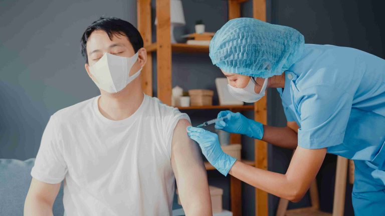 Male patient given flu vaccination by a healthcare worker.