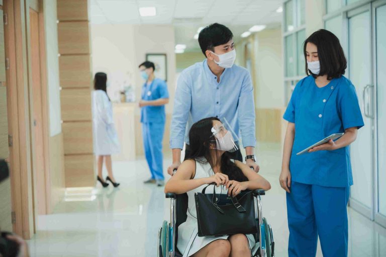 Healthcare worker speaking with a patient on a wheelchair.