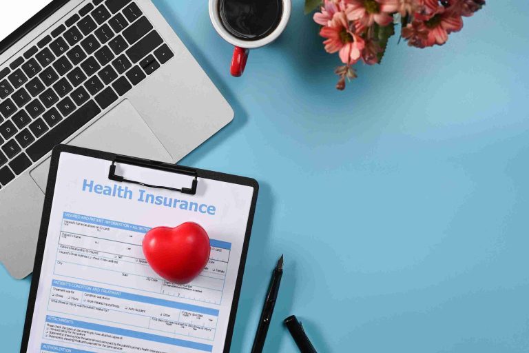 A picture of a laptop, coffee, and health insurance form.