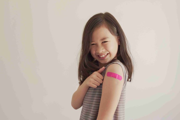 Young asian girl showing off her vaccinated arm.
