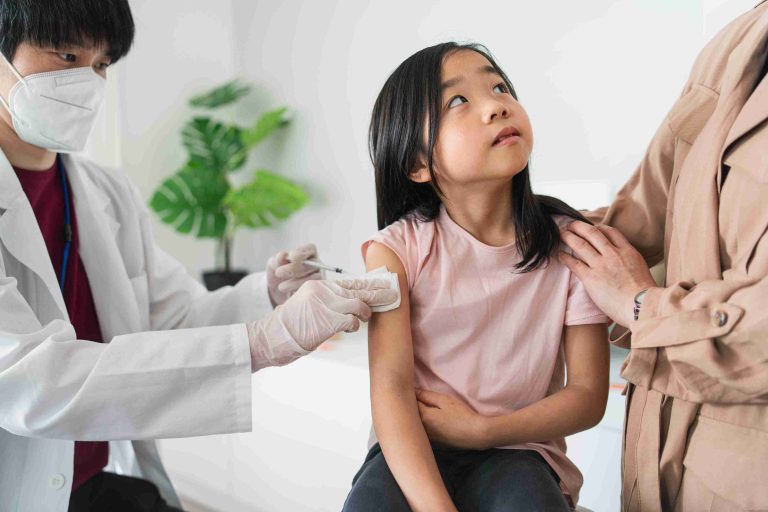 Child looking up at her mother while getting vaccinated.