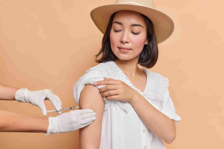 Woman wearing a fedora getting a travel vaccine.