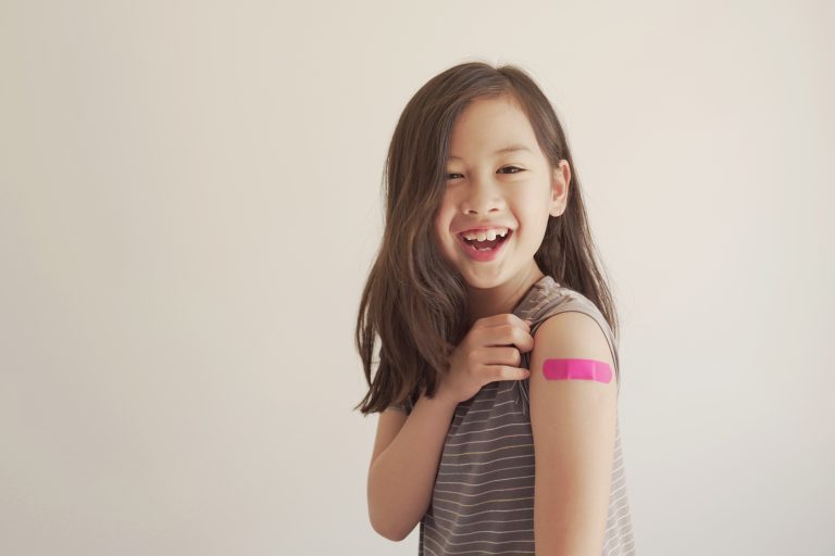 Smiling asian girl showing off her vaccination.