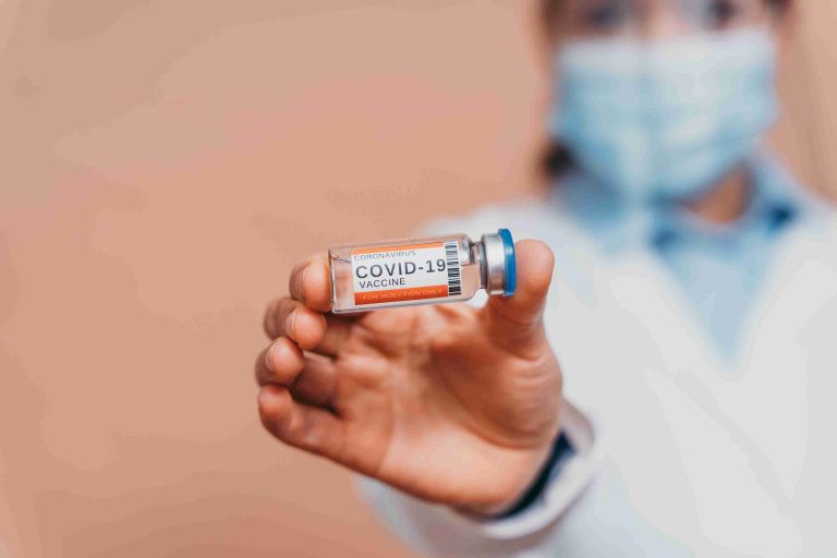 Healthcare worker holding a COVID-19 vaccine vial.