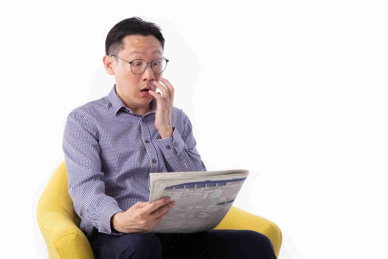 Man surprised reading the newspaper.