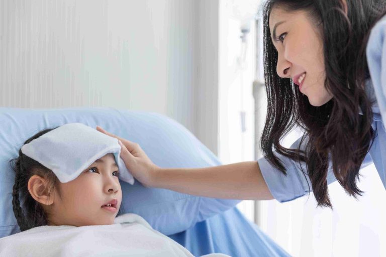 Little girl with fever lying in bed and comforted by the mother.