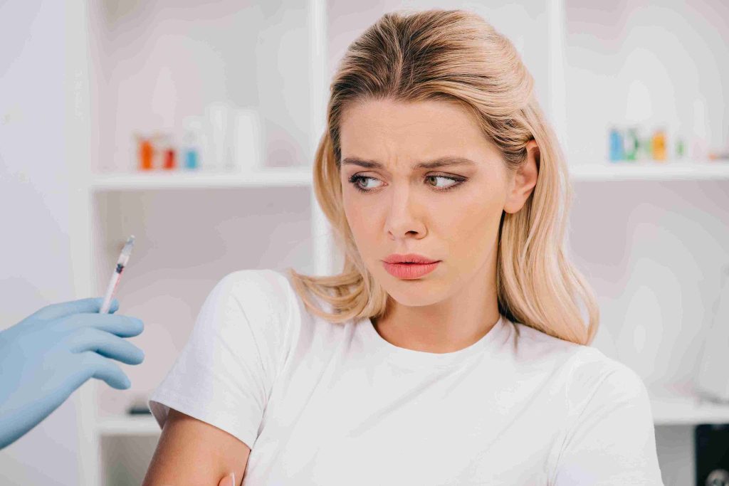 Woman looking at a syringe and looking hesitant.