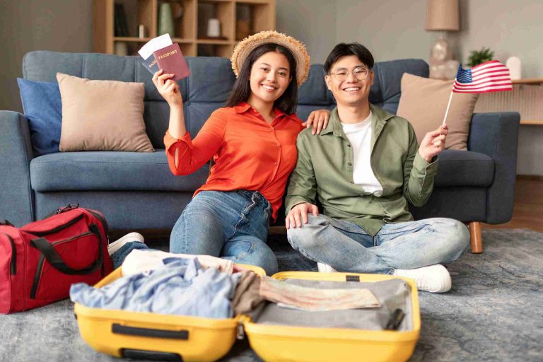 Asian couple holding a US flag and packing for their trip.