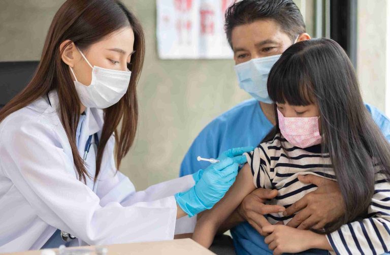 Young child getting vaccine shot from a pediatric doctor.