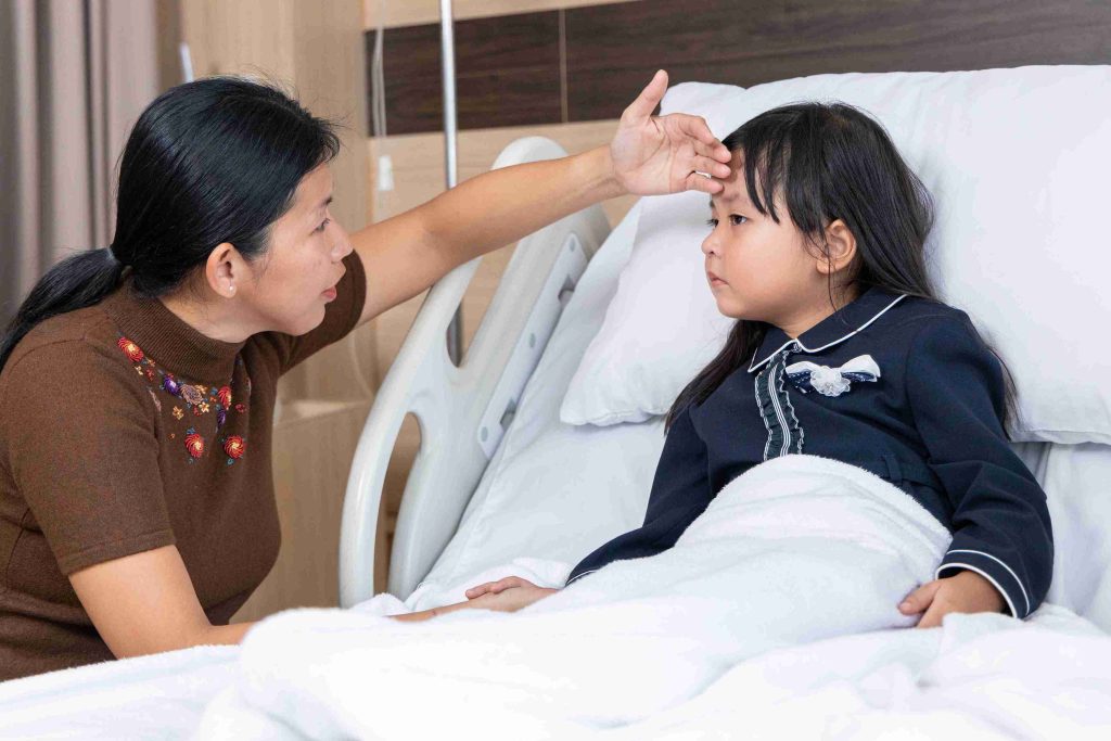 Child with fever in the hospital bed with her mother.