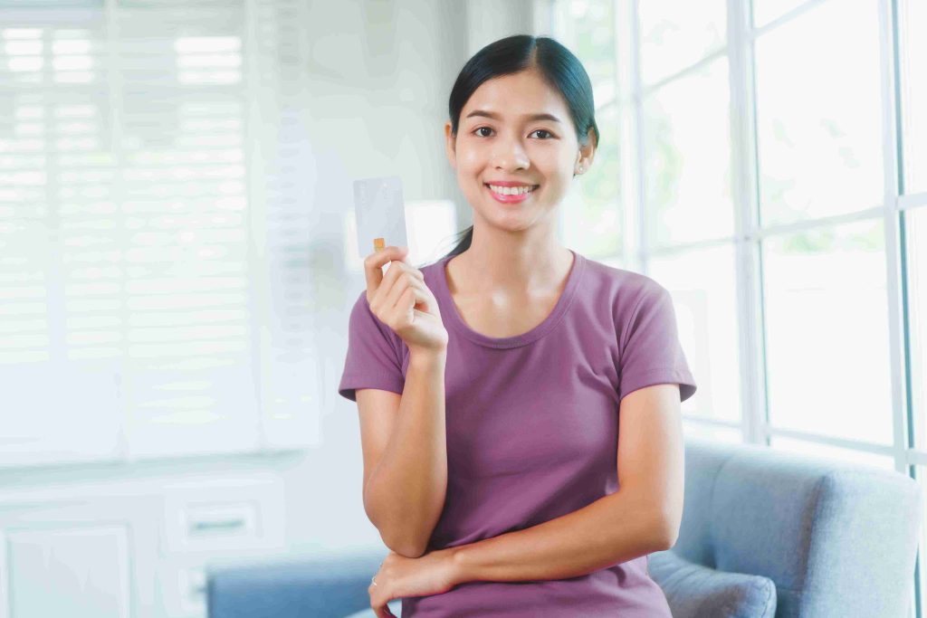 Woman holding her CHAS card while smiling at the camera.