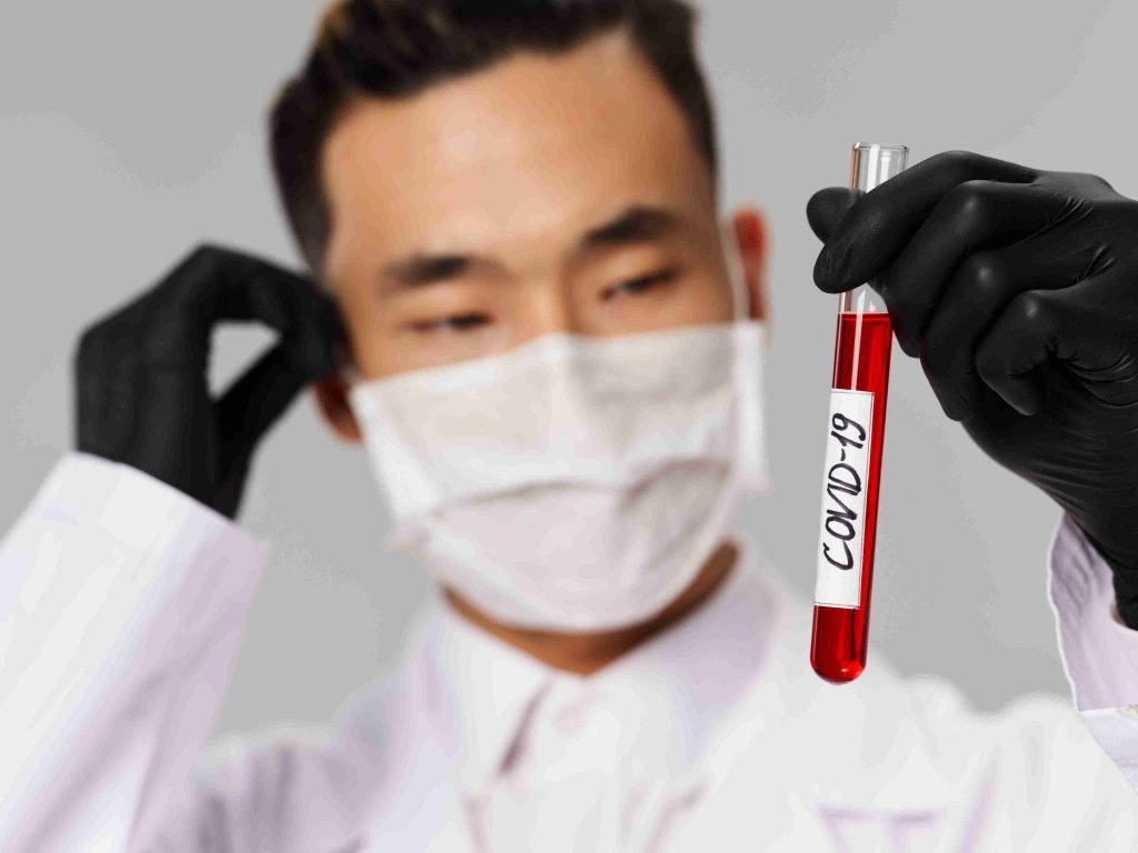 Healthcare worker holding a vial with red liquid and marked COVID-19.