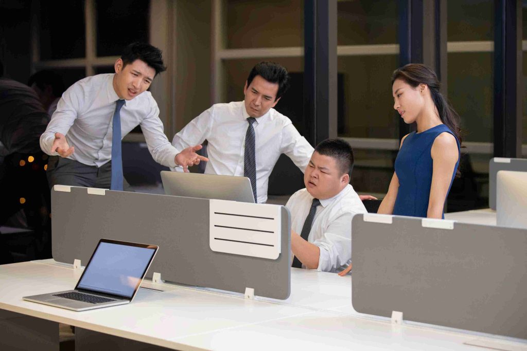 People in the office looking at a computer and looking puzzled.
