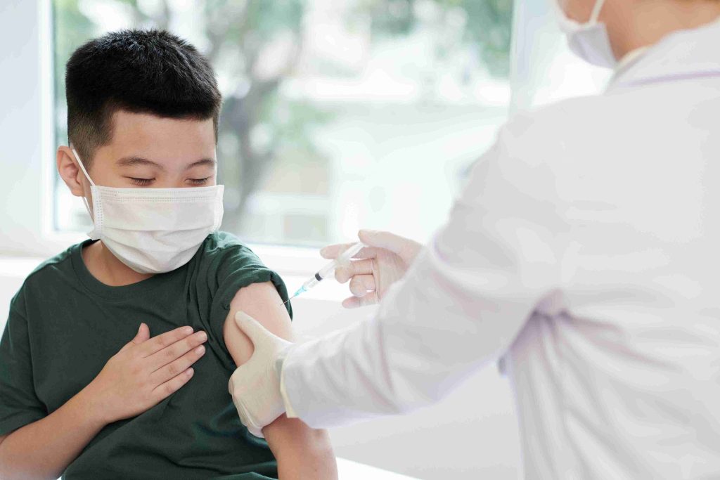Little boy getting vaccinated by a healthcare worker.