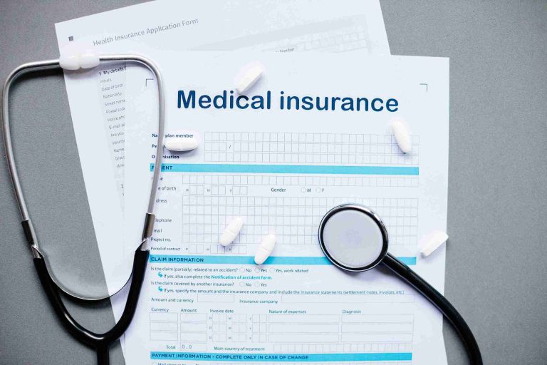 Image of a medical insurance form with tablets and stethoscopy on top.