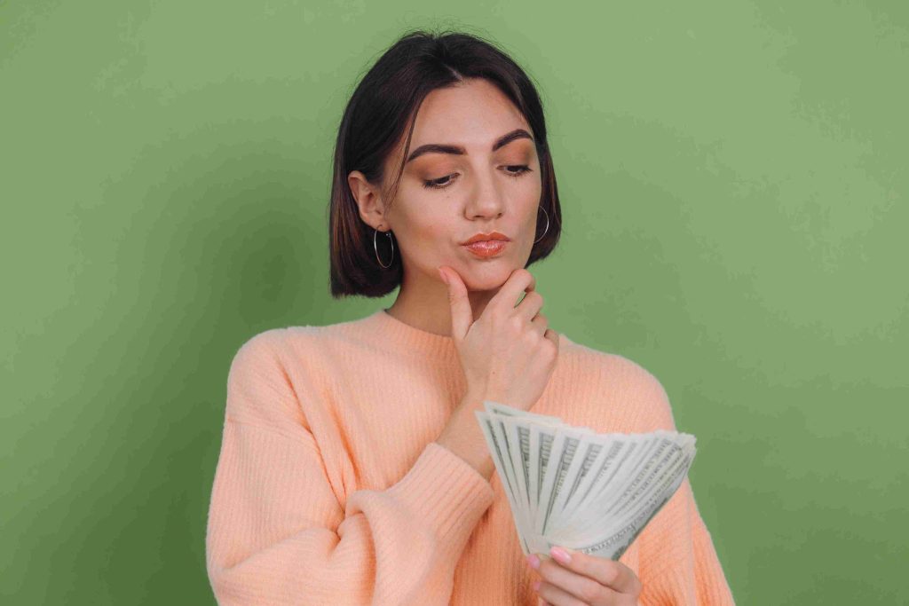 Woman holding dollar bills and thinking.