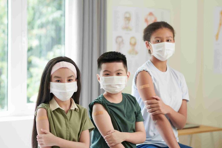Three children showing off their vaccinated arms.