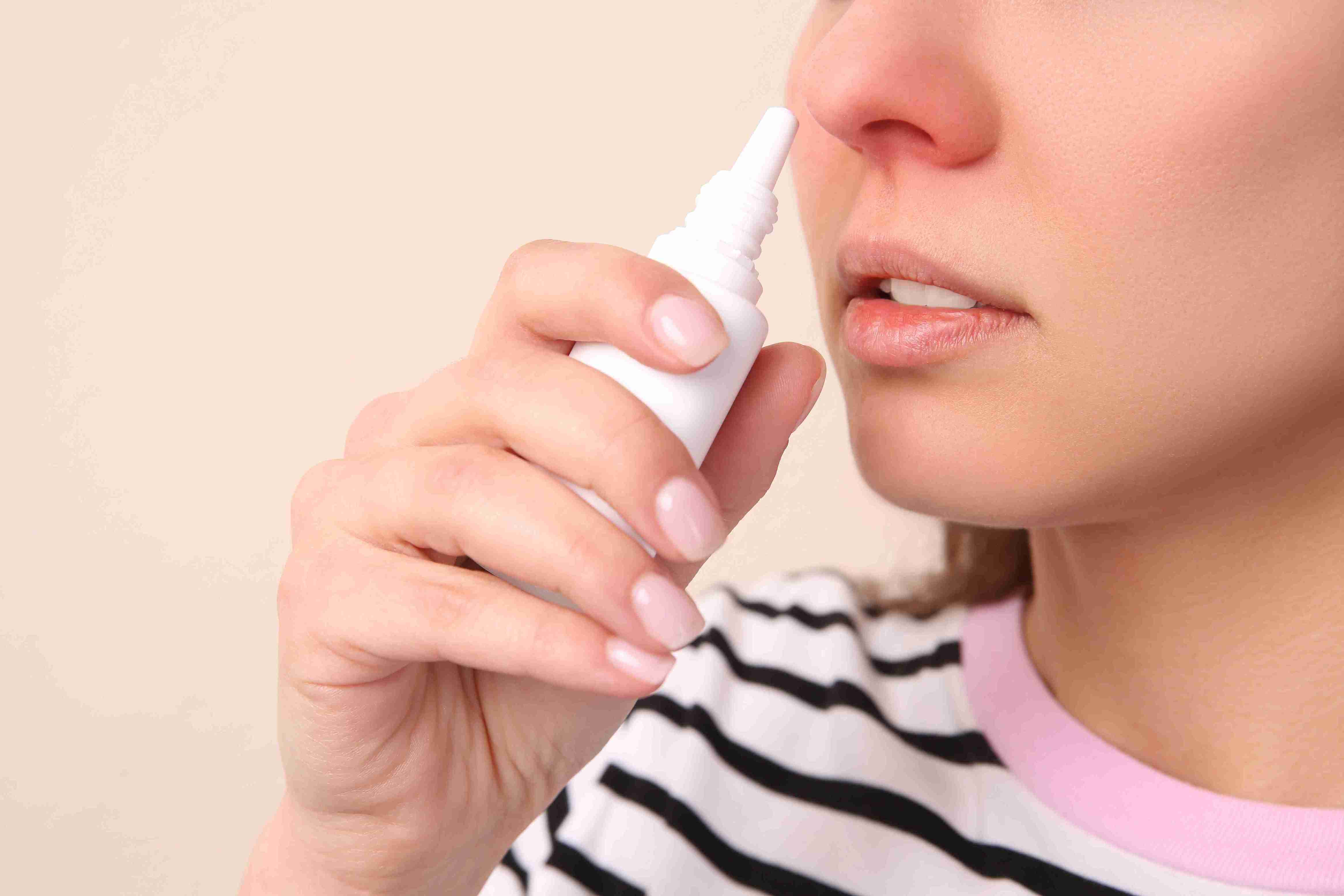 Woman using a nasal spray.