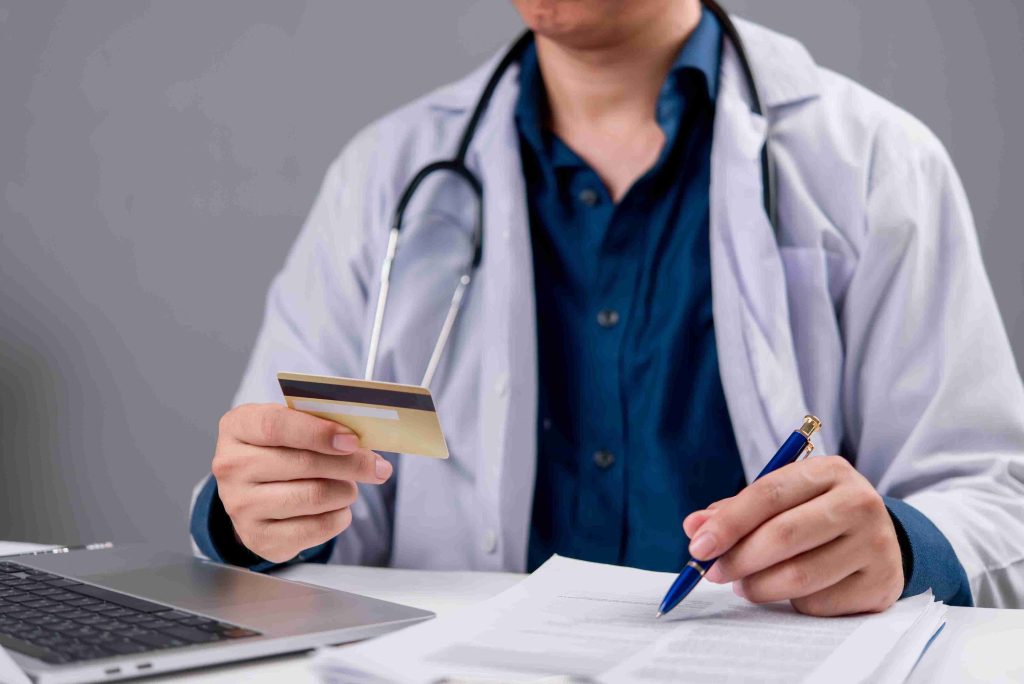 Doctor holding CHAS card and processing payment online.