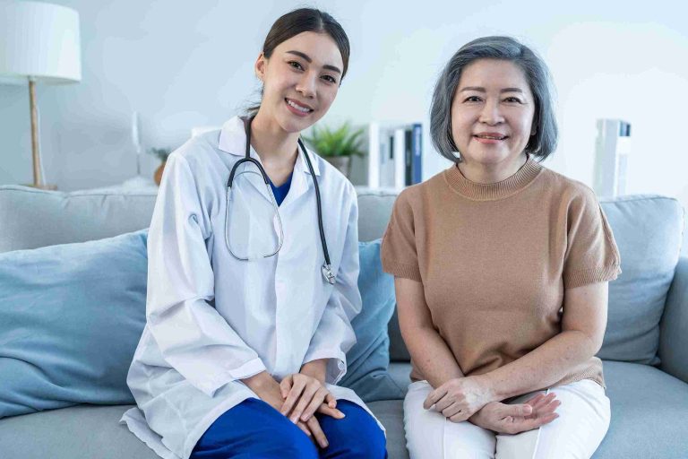 Doctor sitting next to an elderly patient and smiling.