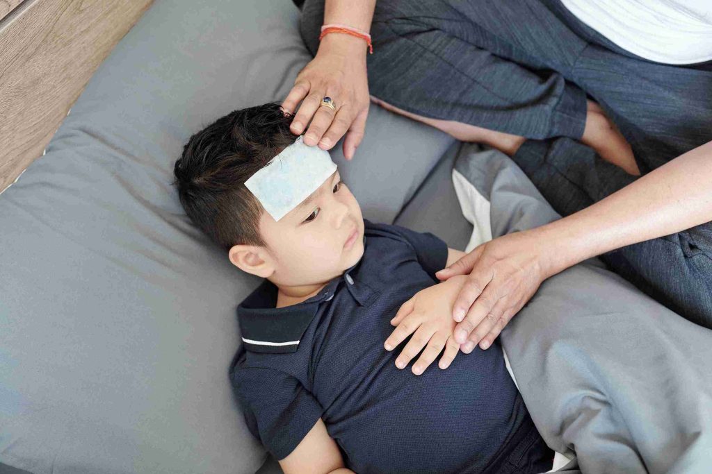 Adult attending to a toddler with a fever cooling patch.