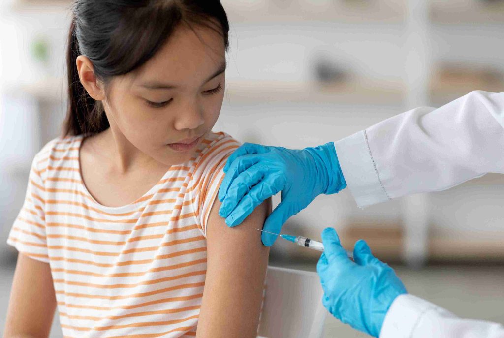 Young girl getting vaccination on her arm.