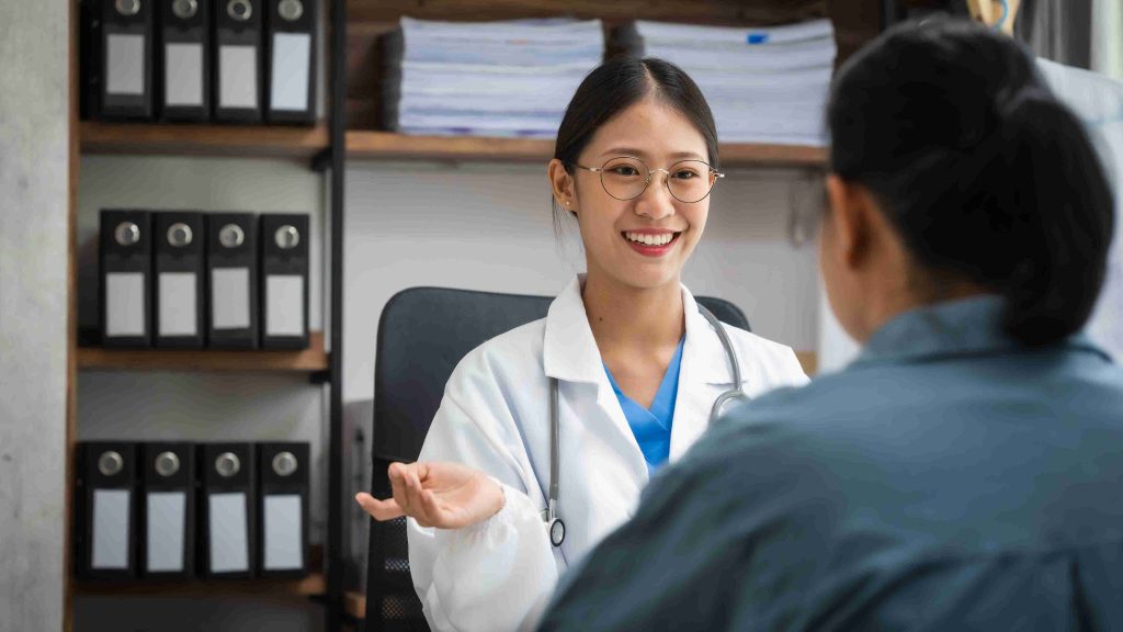 Healthcare worker smiling to an elderly patient during consultation.