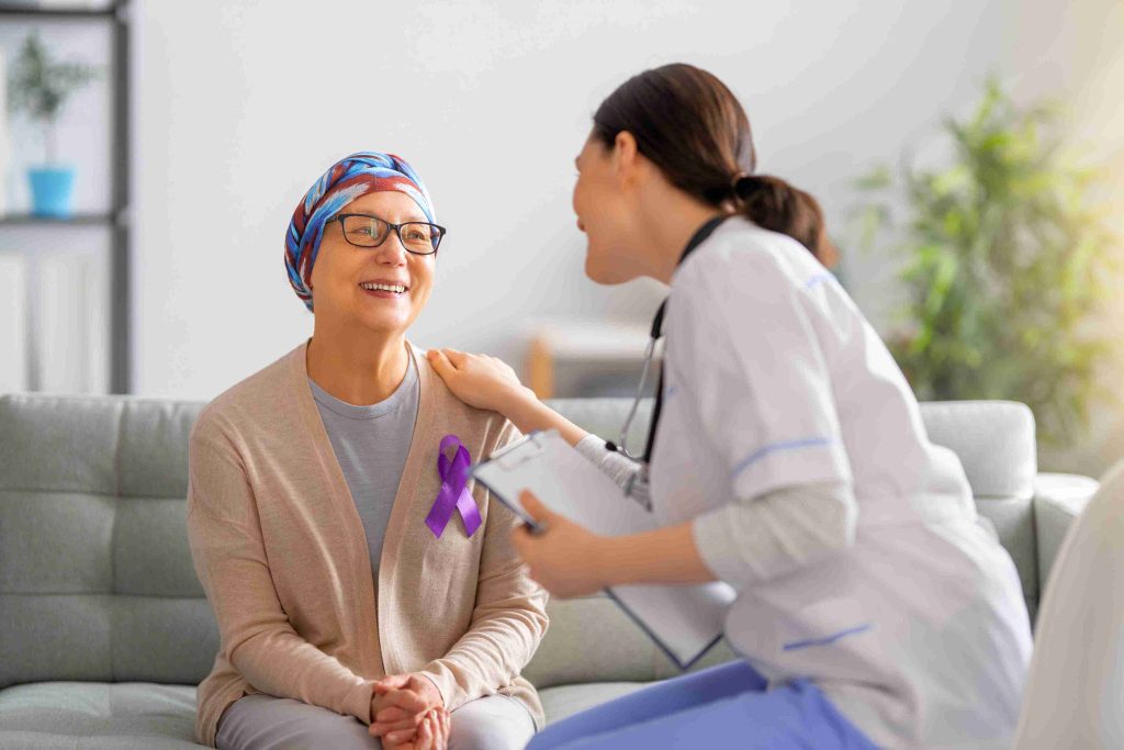Healthcare worker speaking with a smiling cancer patient.