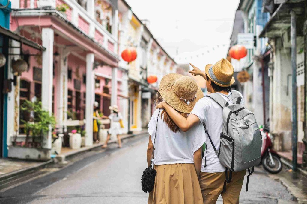 Travelling couple with their backs to the camera as the man points toward something ahead.